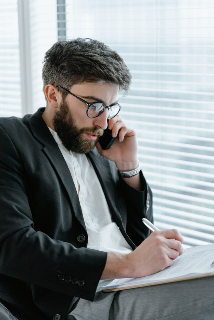 photo of man on the phone taking notes at his desk.